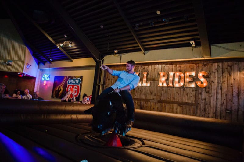 Man in Blue Shirt Rides Mechanical Bull